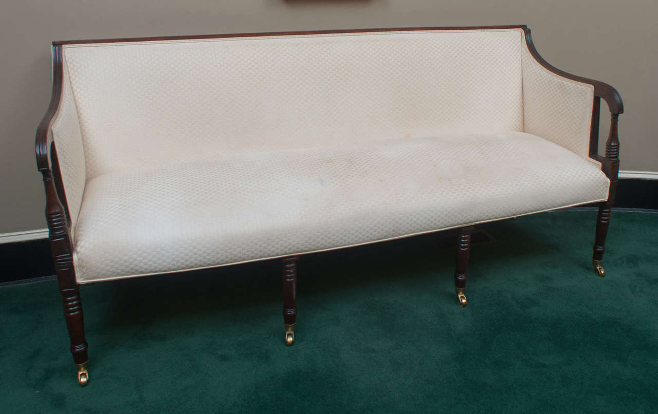 This excellent Federal settee has fine reeding, turnings, and carving throughout.  Delicate reeding on the back rail and arms connect to a beautiful hand-carved rosette atop each end of the back rail. Four turned legs with castors in the front and