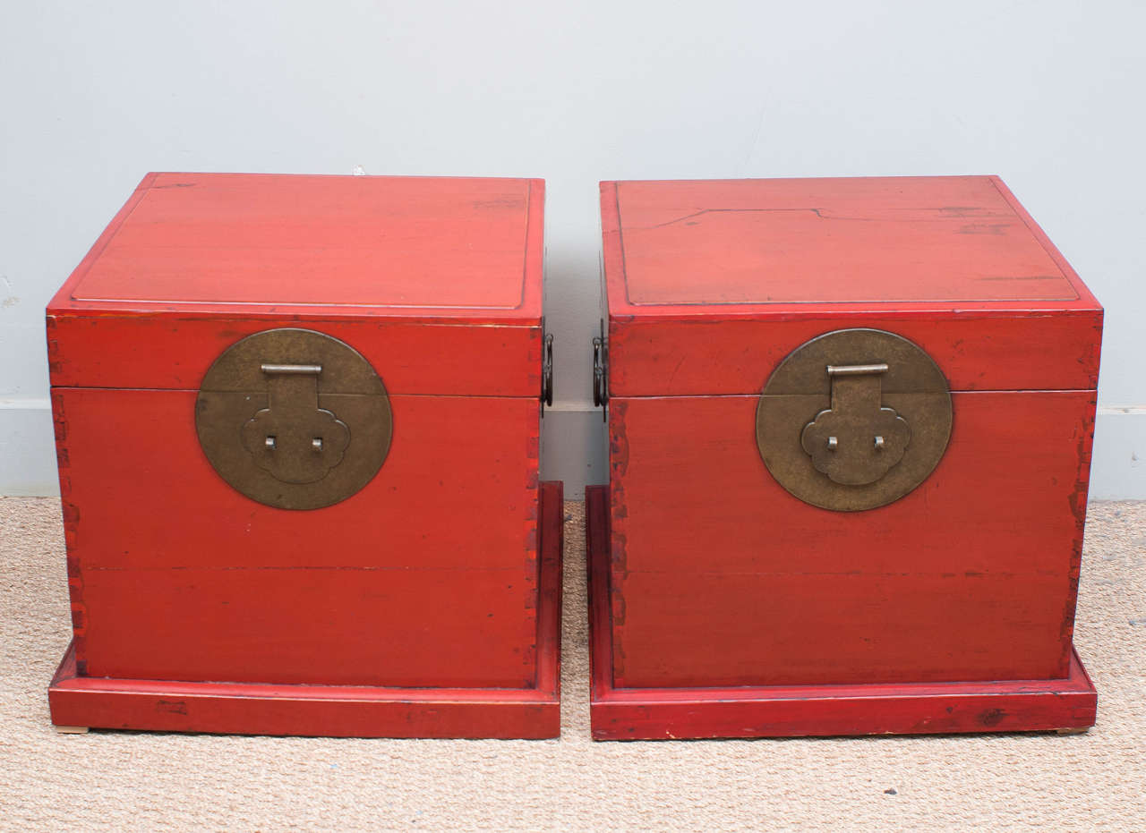 Square red lacquer trunks on base with brass fittings.