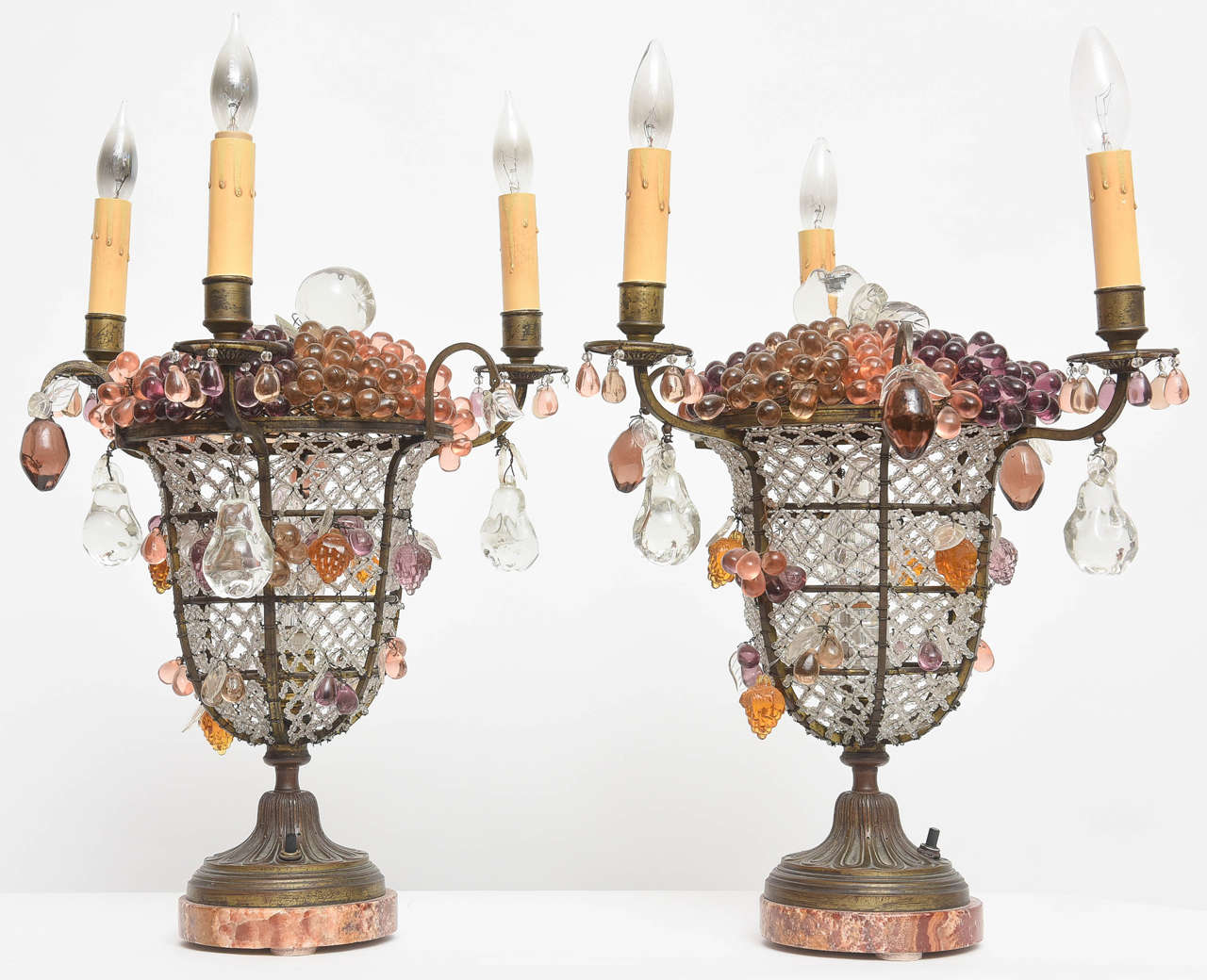 Exceptional pair of very large beaded urn lamps on marble bases. Various glass fruits adorn the basket and arms. Three lights on each.