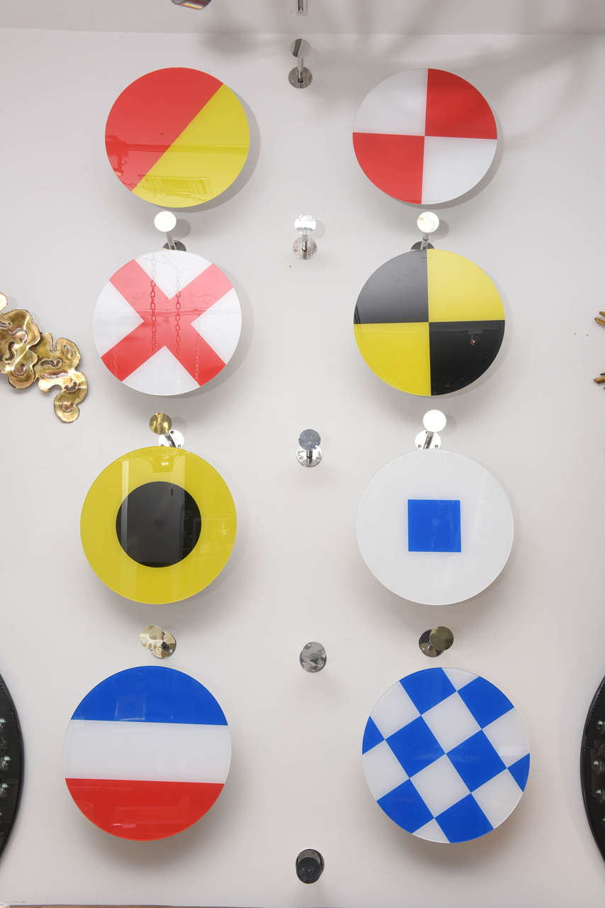 Large wall-mounted display eight Lucite discs with different nautical flag motif. Each piece is separately mounted with chrome mountings-- may be placed in a variety of arrangements. There are 19 chrome pieces measuring at 3