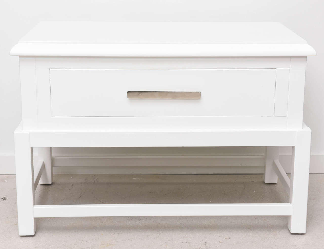 Pair of satin white lacquered bedsides with a single large drawer and nickel hardware.