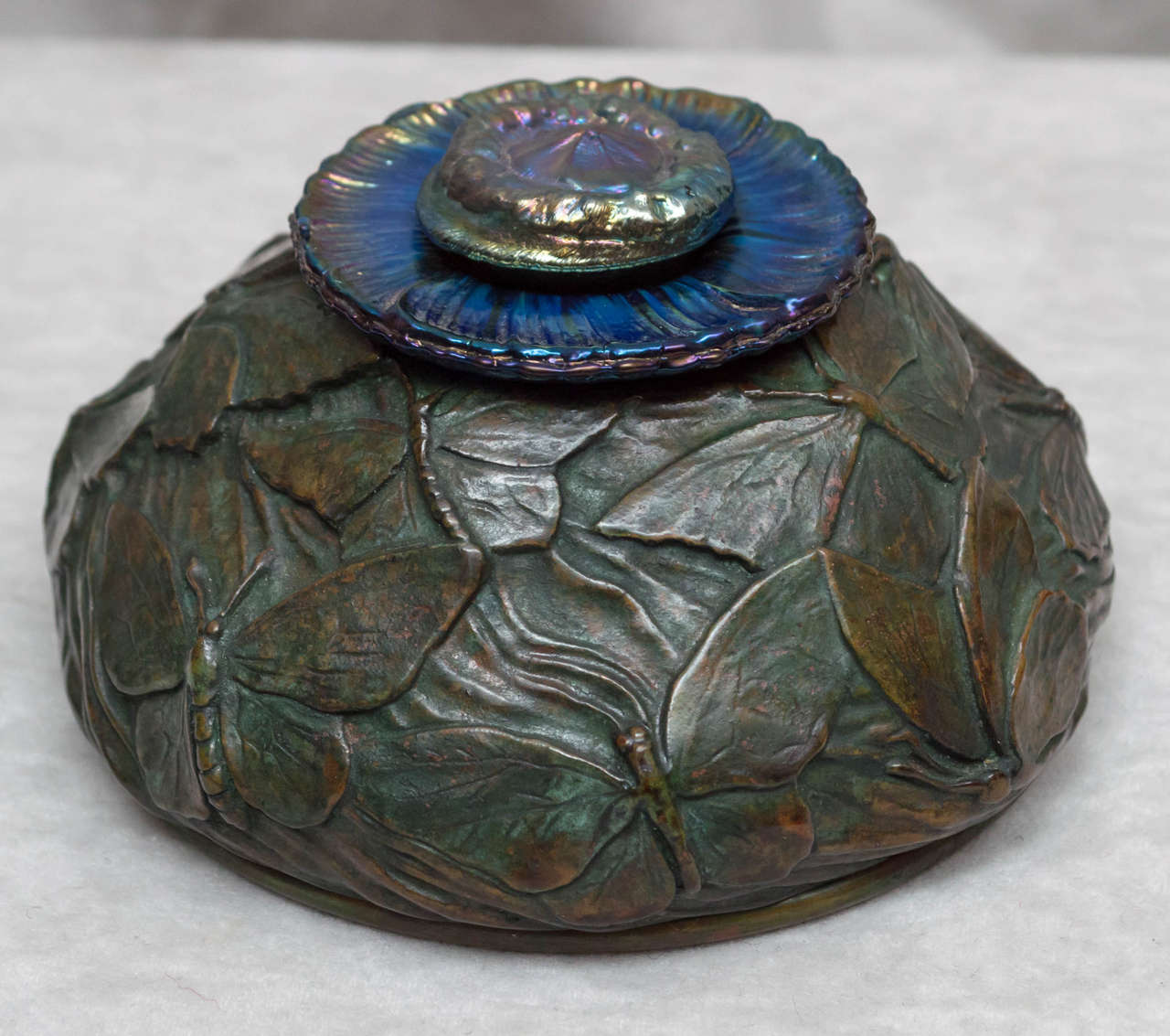 A very special piece of Tiffany is what we are offering. All cast in bronze with exceptional patina, and iridescent blue glass liner and lid. All there, nothing missing or damaged.
 Properly signed and not as small as the dimensions indicate. A
