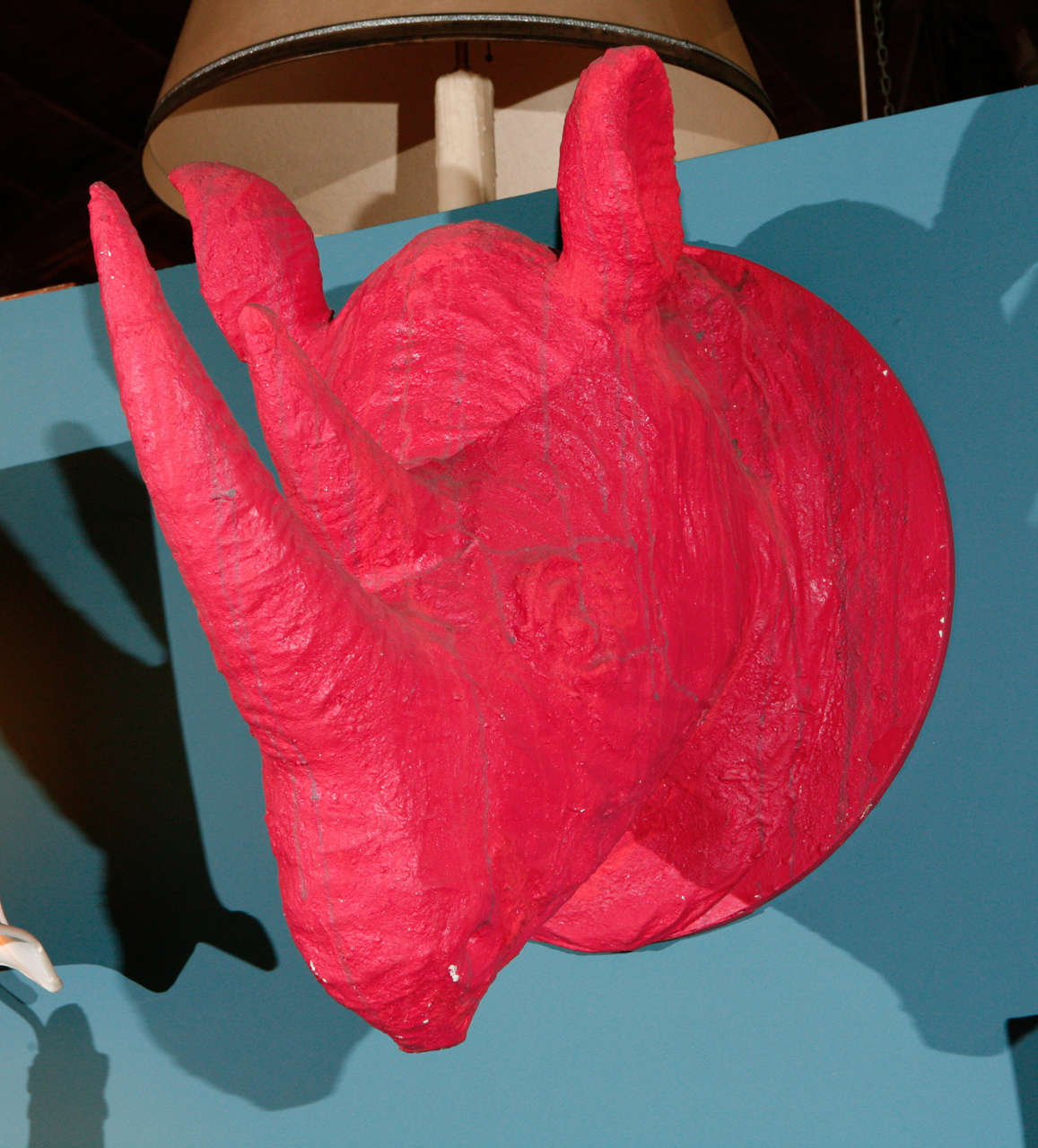 A playful pair of red rhino wall sculptures. Made of paper mache in a a bright red color with accented with free form gray lines.