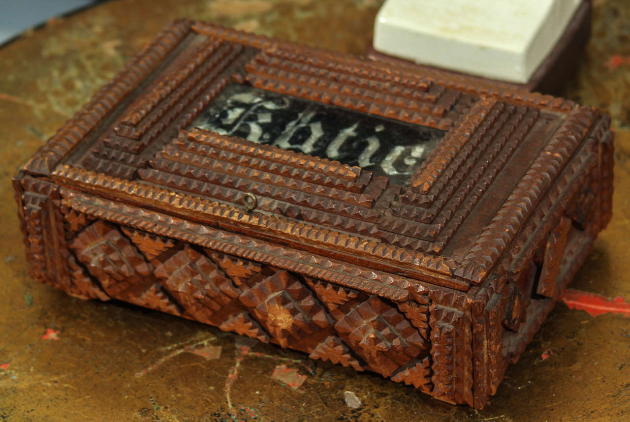  detailed tramp art box with reverse painted/foiled glass name plate.  lined in menswear striped vest lining.     missing elements on left side of box, damage to right hinge with old repair and glass is in 2 pieces, but secure in box.