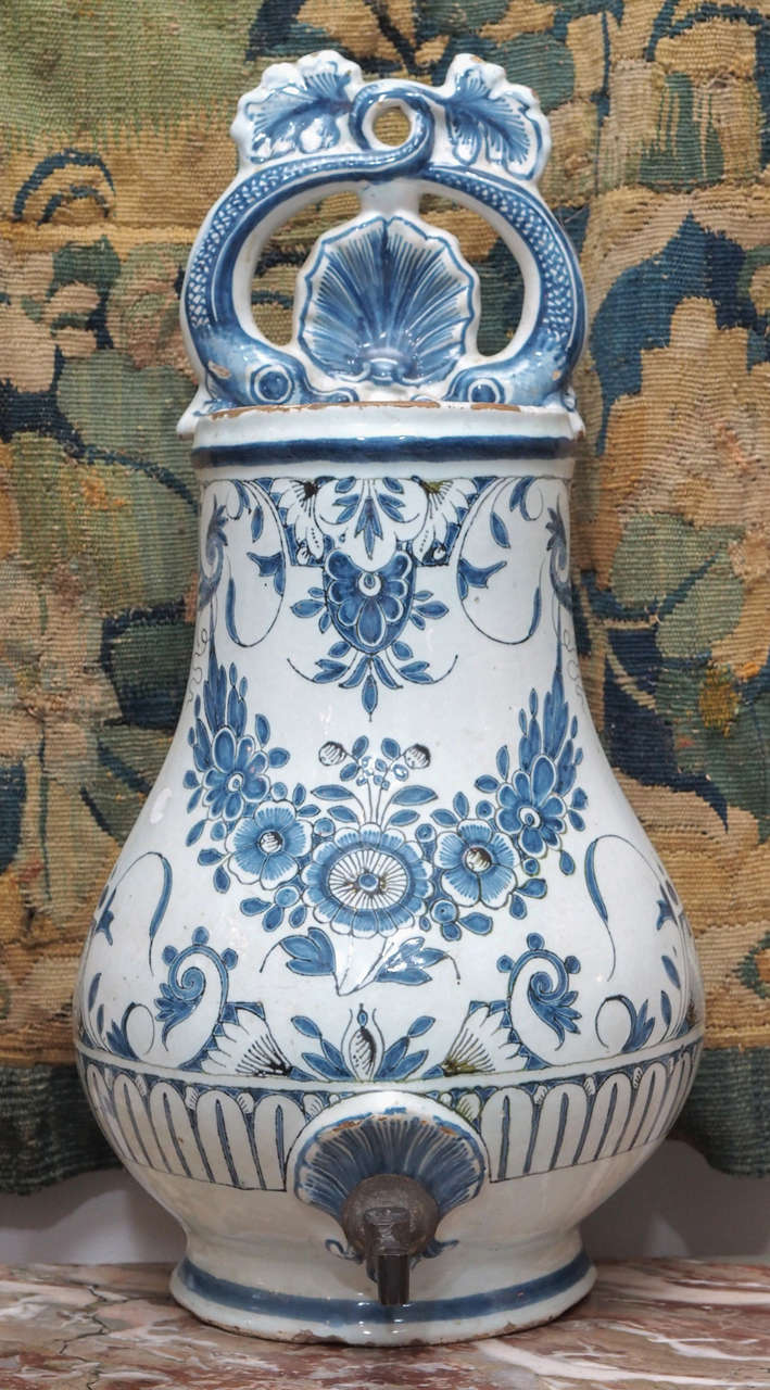 A faience vase, the top part of a lavabo, in blue and white, particularly interesting because of its pierced, decorative cartouche of dolphins, their tails intertwined.  We like to use these vessels as vases for flowers or greens, the generous size,