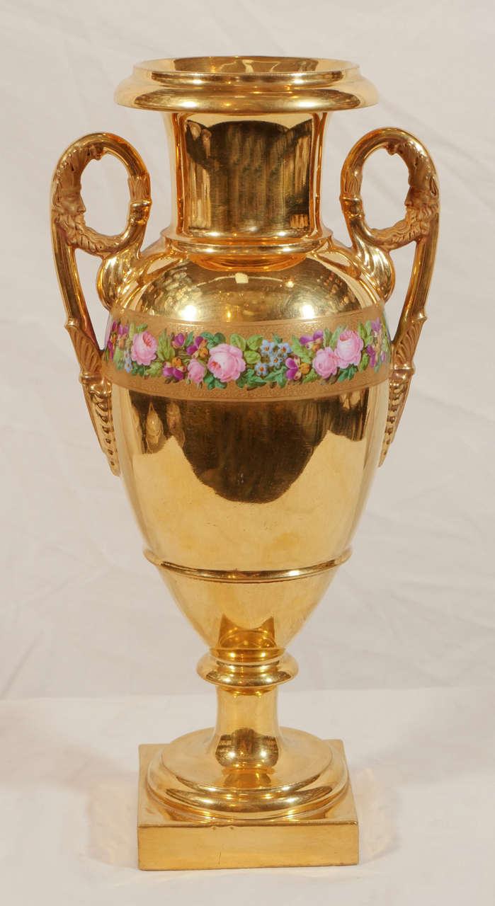 Nous avons le plaisir d'offrir cette paire de vases manteaux en porcelaine de Paris dorée, de style Empire, vers 1840. La dorure sur ces vases est éblouissante. La délicate bande de fleurs et les poignées mates soulignent la qualité miroir de l'or.
