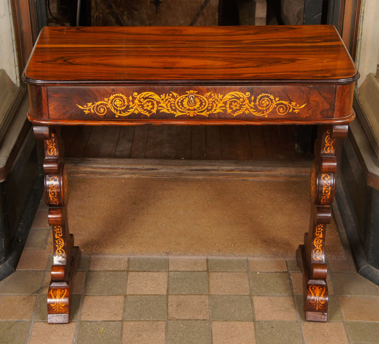 This fine and lovely small french writing table would also work well as a small console as it is flat and undercoated along the back side. The piece  is constructed as a molded top with rounded front  corners above a frieze drawer inlaid with