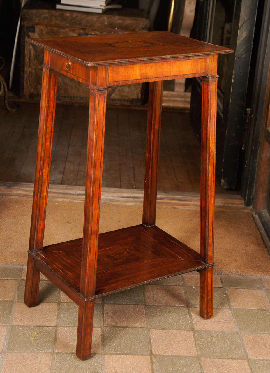 This lovely small candle stand has a single drawer and candle slide at opposed ends to the inlaid top. The miter paneled veneered  top is centered with a oval floral cartouche. The borders of the legs, top and lower shelf are also veneered  in