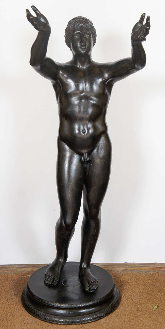 This large and impressive cast bronze figure of a youth with up raised arms is well modeled and  retains its original patina giving the figure a soft and supple  life like nature. The face showing a distant serenity is typical of the best classical
