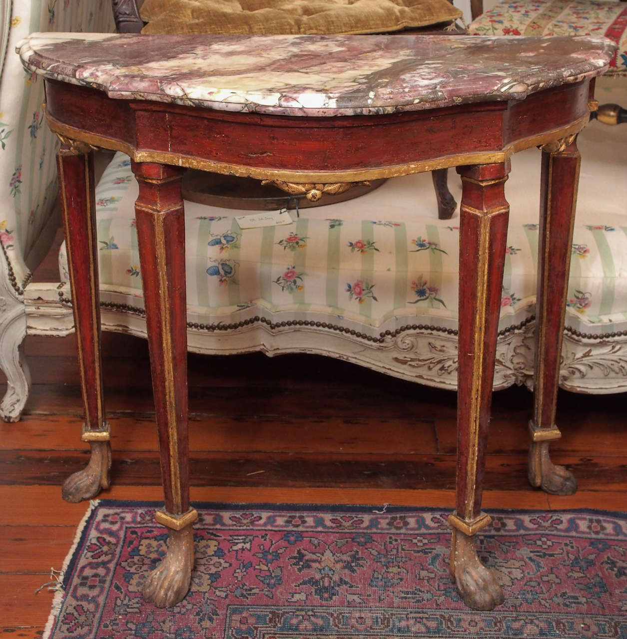 Painted and parcel gilt Console table with Marble top and four legs terminating in animal feet. In a serpentine shape.