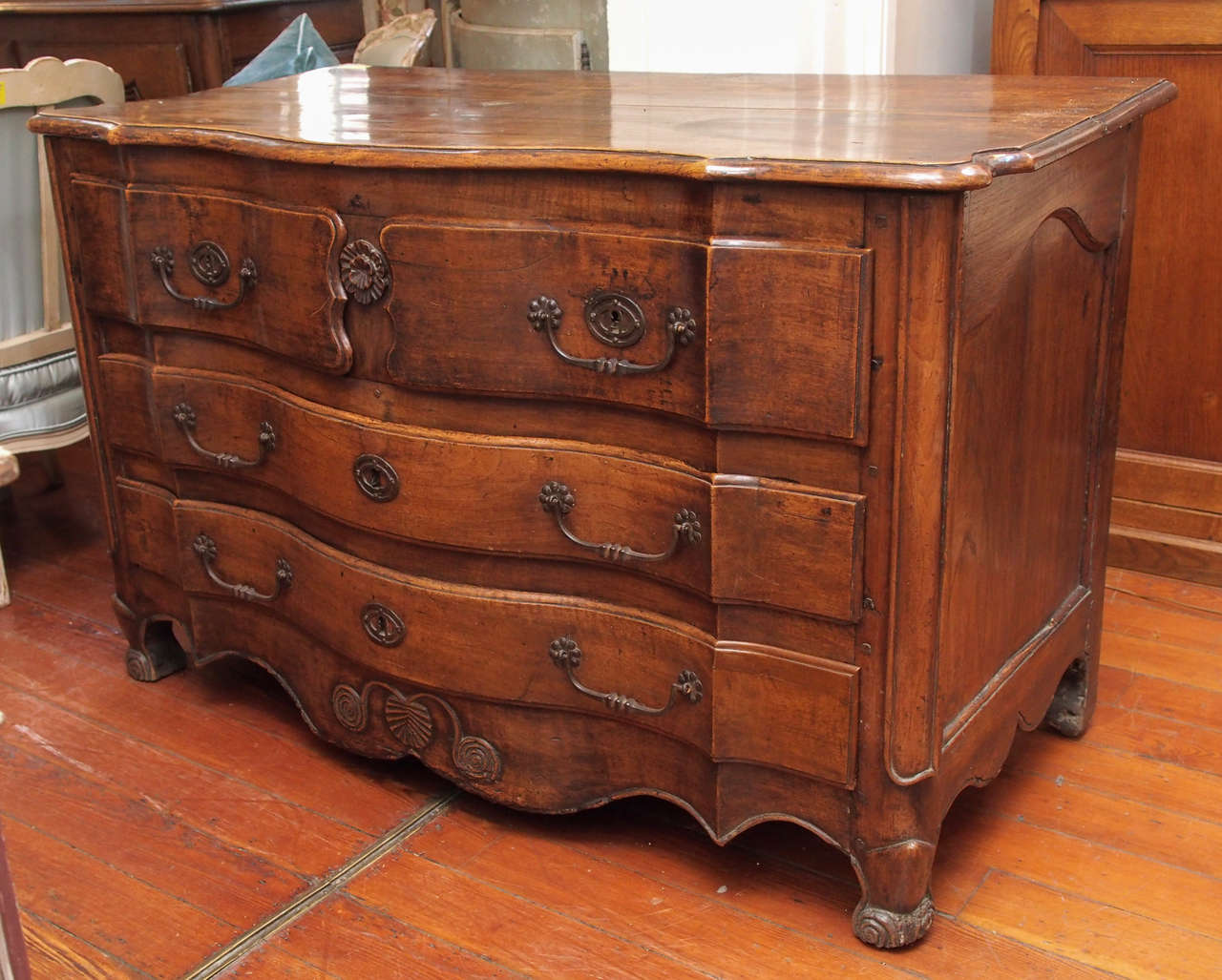 18th century Louis XV  serpentine  walnut commode with 4 drawers on 3 levels.
Period piece, provincial work. Scrolled feet, carved shell motif on the bottom.