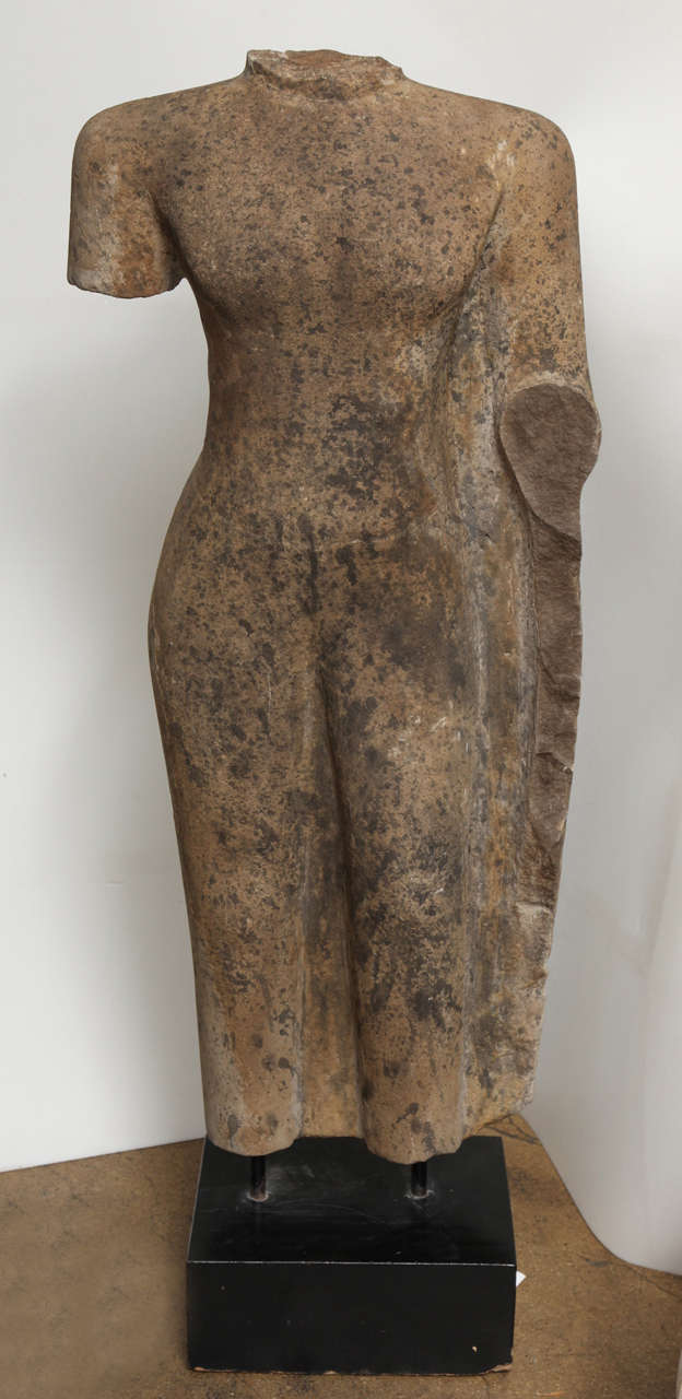 A carved stone male torso, weathered and worn, mounted, from Thailand