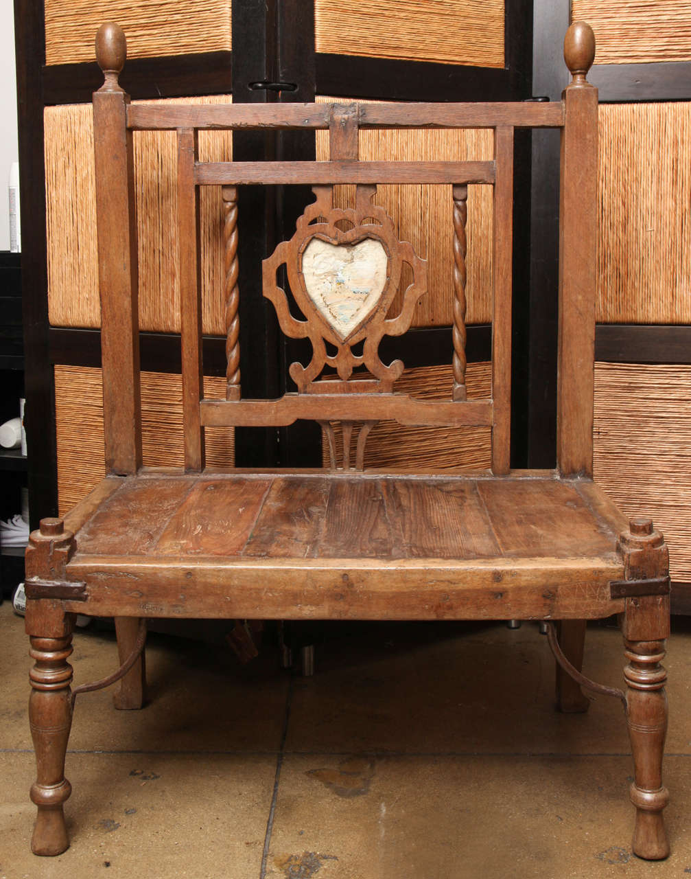 A wood bench from India with a glass heart medallion and finials.