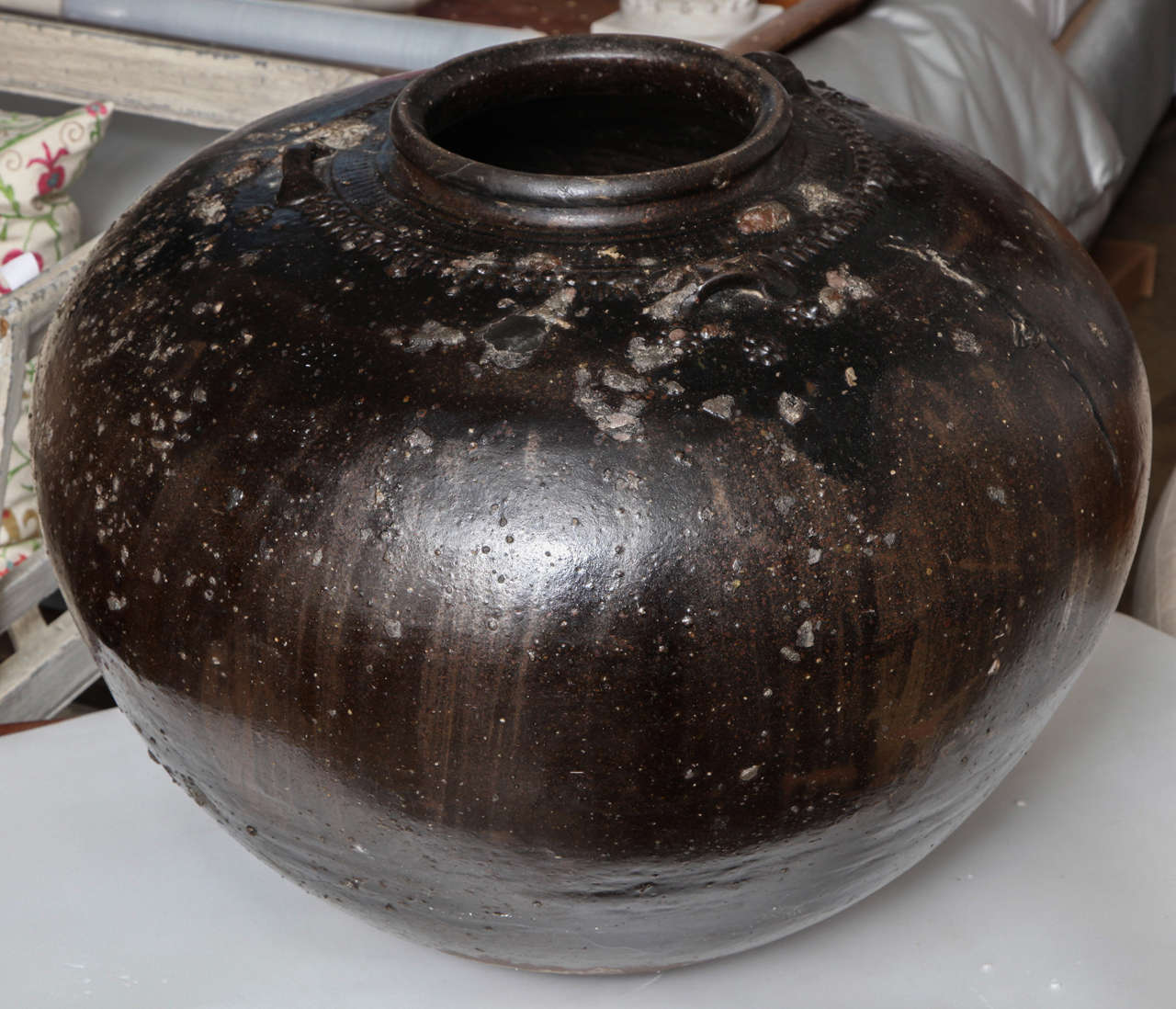 A large clay pot from India, dark glaze.