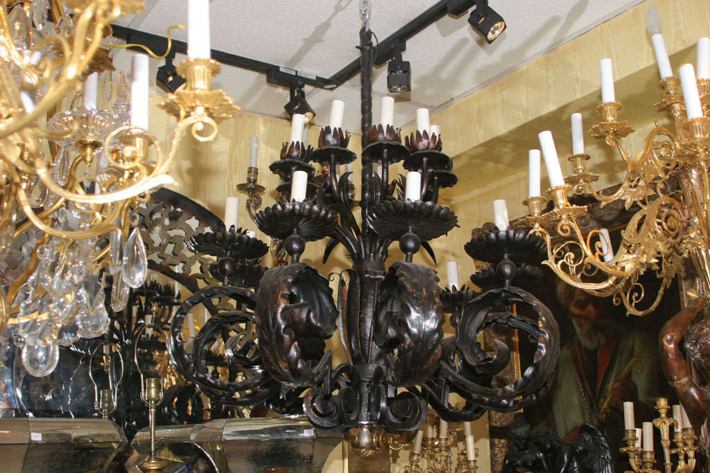 This fabulous chandelier must be seen in person to be truly appreciated. The generous proportions of the heavily stylized acanthus leaf arms seems imposing at first, but is balanced by the deep brown or black color of the chandelier, lending an