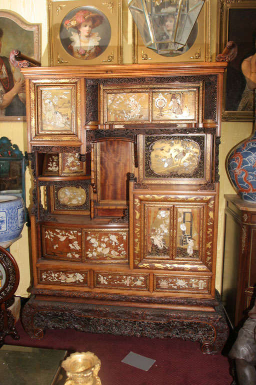 This massive display cabinet serves well as both an artistic and decorative object addition to your collection, replete with gold lacquer, inlaid ivory and mother of pearl figural pearl and crane designs.