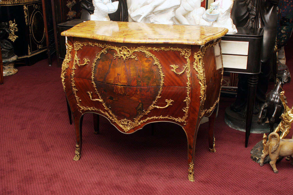 A very fine and charming 19th century commode in the Louis XV style. The commode has extensive gilt bronze mounts throughout, and a heart shaped ormolu motif framing a Vernis Martin courting scene.