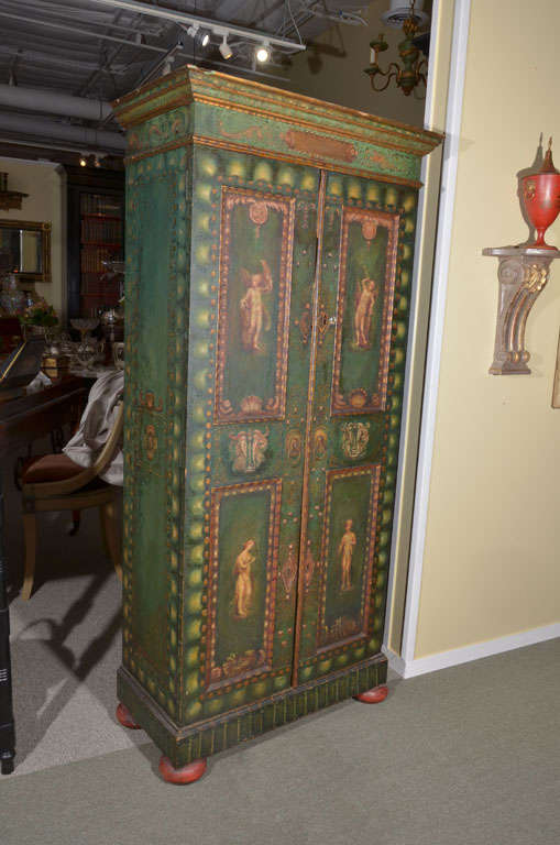 Small green two-door cabinet with neo Classical style painting on red bun feet from England.
This cabinet was purchased Christie's South Kensington in London in 1996.  The catalog description follows:
107 A green-painted and gilt-heightened