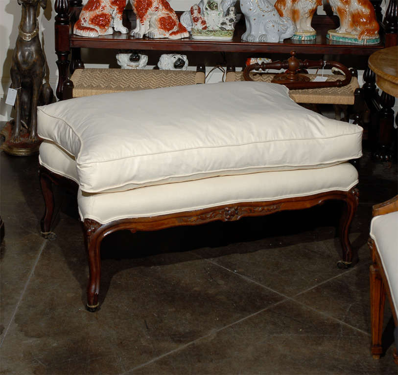 Large French ottoman with carved legs on castors with new muslin upholstery.