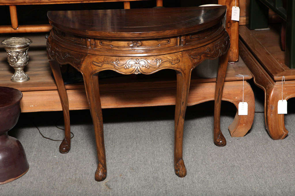 This graceful elmwood demilune table was made in the Shanxi region of Northern China in the second half of the 19th century. Thanks to a recent restoration, the condition of this piece is excellent, and enhances the delicacy of its carving. The wood
