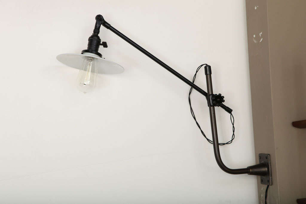Vintage industrial wall-mount swing-arm lamp by O.C. White. USA, circa 1930.  Priced individually; a pair is available.  Metal arms in patinated brass finish with vintage white milk glass disk shades. Includes clear Edison bulbs. 
Custom restored