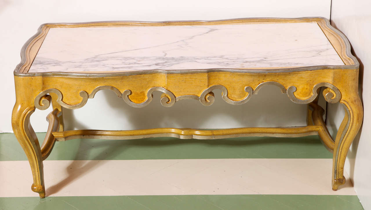 A vintage Baker Furniture Rococo-style coffee table with marble top. The table's yellow finish with silver edge detail is original. Metal Baker stamp on underside of frame.