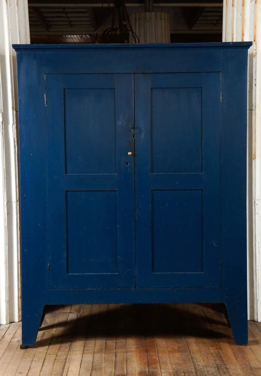 sophisticated cherry cupboard - c,1810 - Ulster County, New York - two flat panel doors - three shelf interior - delicate crown - resting on tall tapered legs - intense blue painted surface over cream