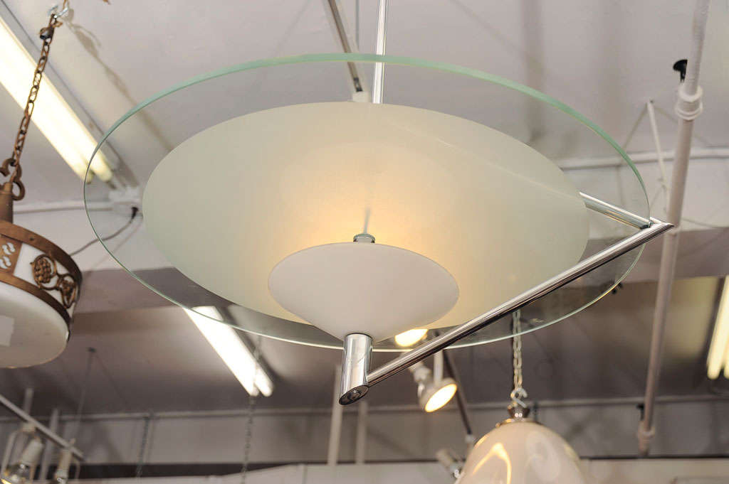 Modern pendant light designed by Daniela Puppa for Fontana arte. Its a clear glass disc with frost glass center mounted on a chrome plated tubular frame. A milk glass shade directs the up- light.