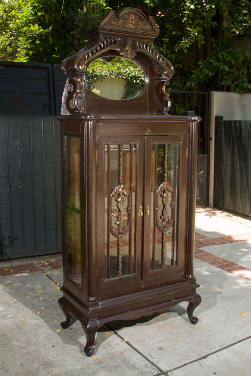 Early 1900s lighted curio cabinet with glass doors.