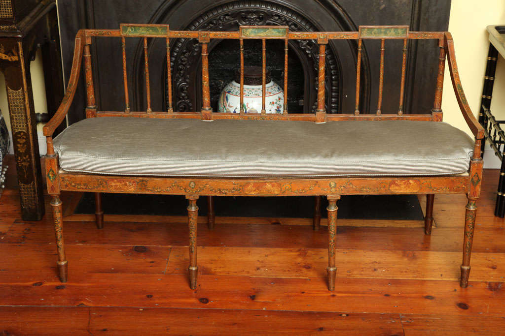 Fine antique Regency painted faux satinwood triple back settee with finely turned vertical spats centered by rectangular panels decorated with classical figures above downswept arms, squab cusion and an apron decorated with classical swags centered