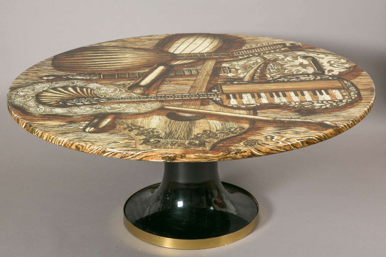 Circular coffee table with music instruments design, 1950s, by Piero Fornasetti (Italy, Milan, 1913–1988).
Brown harmonized laminated serigraphied wood top. Black and gilt brass bobina base. 
Original label.