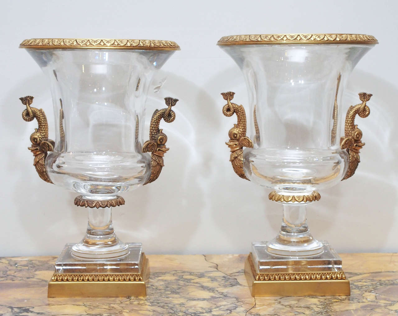 Pair of Crystal Campagna form gilt bronze mounted urns with dolphin handles.
