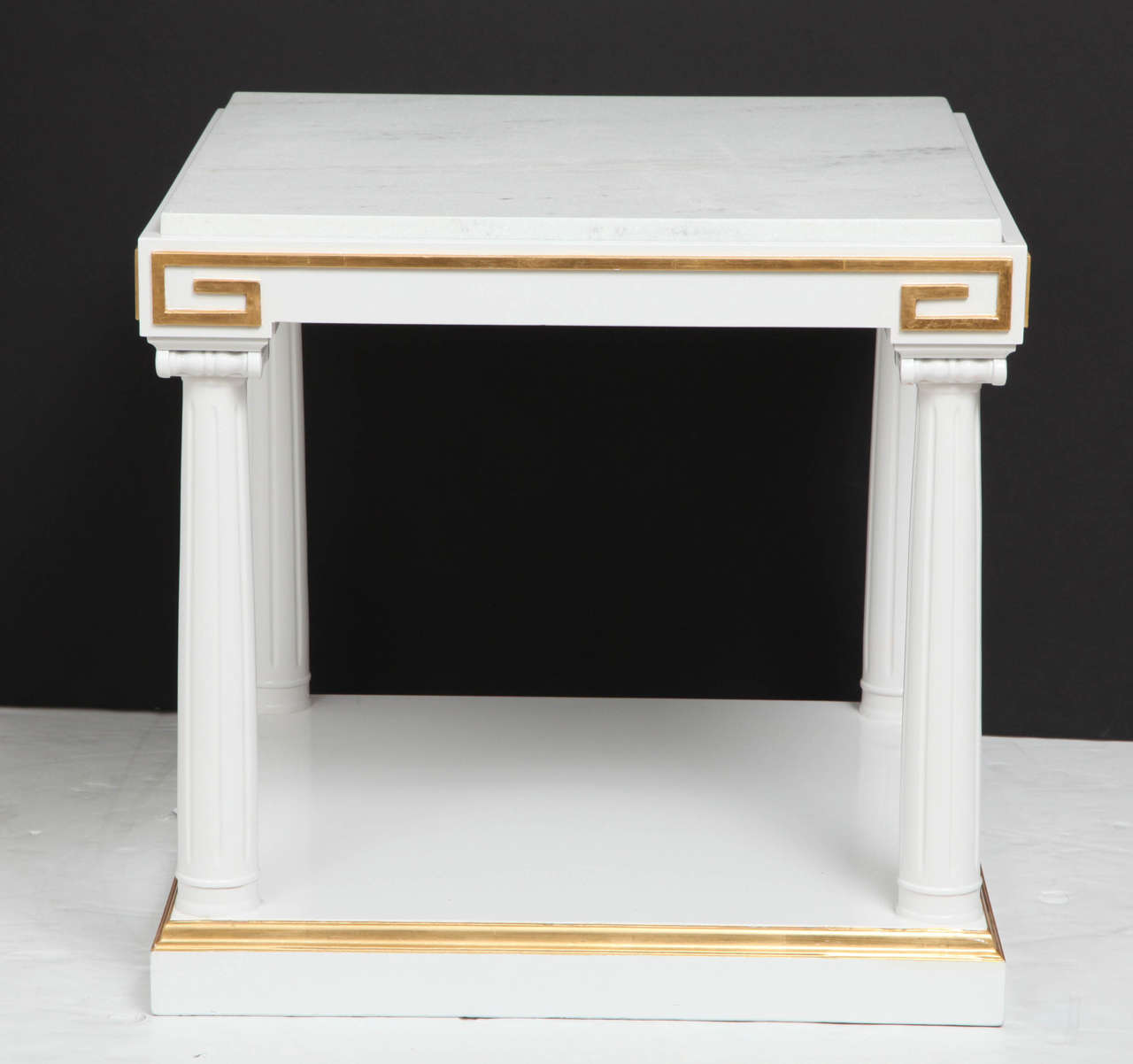 Pair of Neoclassical influenced side tables with fluted column supports and capitals in white lacquer. Tables also feature gold leaf Greek key details and white marble quartz inset tops.
