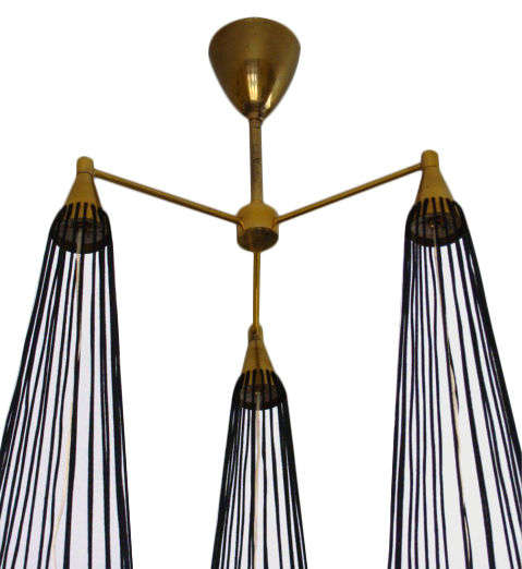 Italian chandelier designed by Angelo Lelli for Arredoluce.

Three handblown frosted glass cones suspended in black wire cages. Hanging with black cords and brass rings and brass finials.