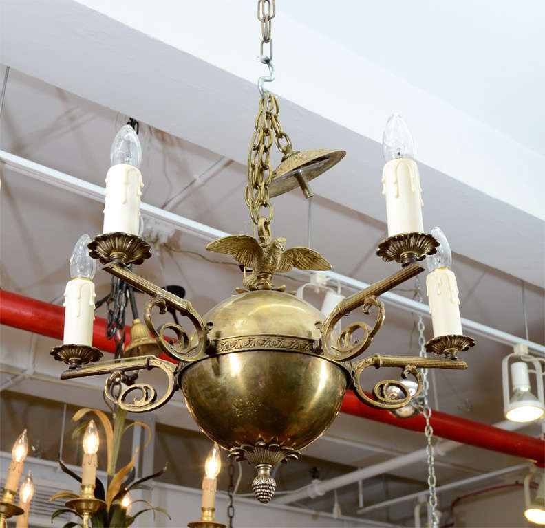 This five light fixture is made of brass in the federal style. The piece has scrolling, vegetal form arms and an eagle on the top.