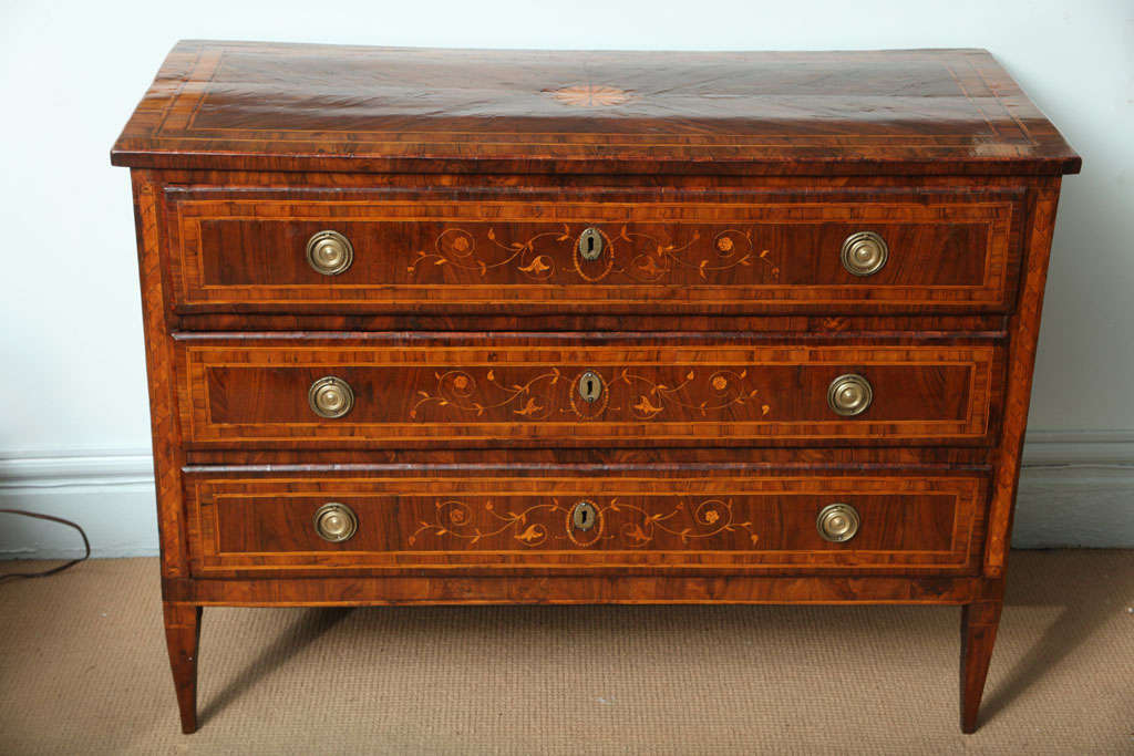 A late 18th century northern Italian neoclassical marquetry inlaid commode; the rectangular top with inlaid and shaded fan patera, above three drawers, having inlaid vines and flowers and oval banding around the escutcheons, original ring handles,