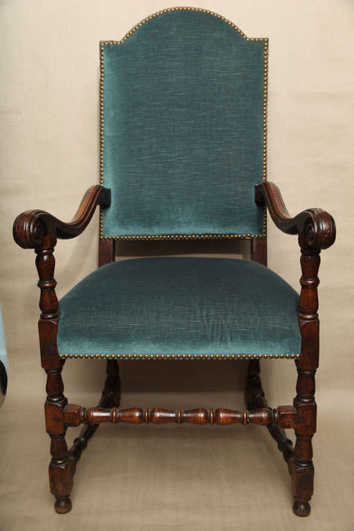 Fine early 18th Century walnut baroque armchair, the upholstered arched back over shaped and carved scrolled arms the turned legs joined by turned stretchers, recently upholstered, the whole with rich color