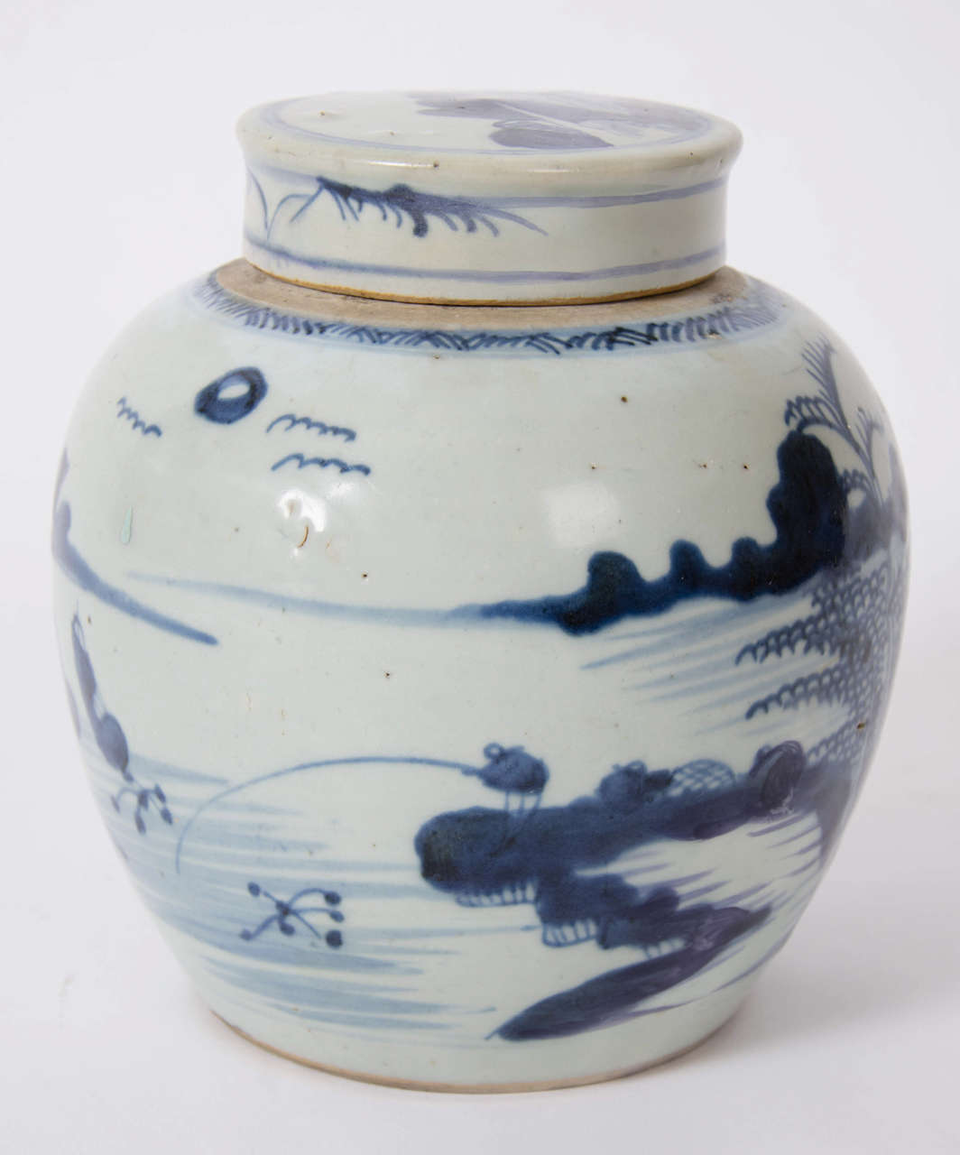 This is a heavy CHINESE porcelain Jar with lid

The jar is CANTON decorated with a cottages scene by the water also showing what looks like two fishing boats on the water with their nets. There is also a border pattern around the top of the jar