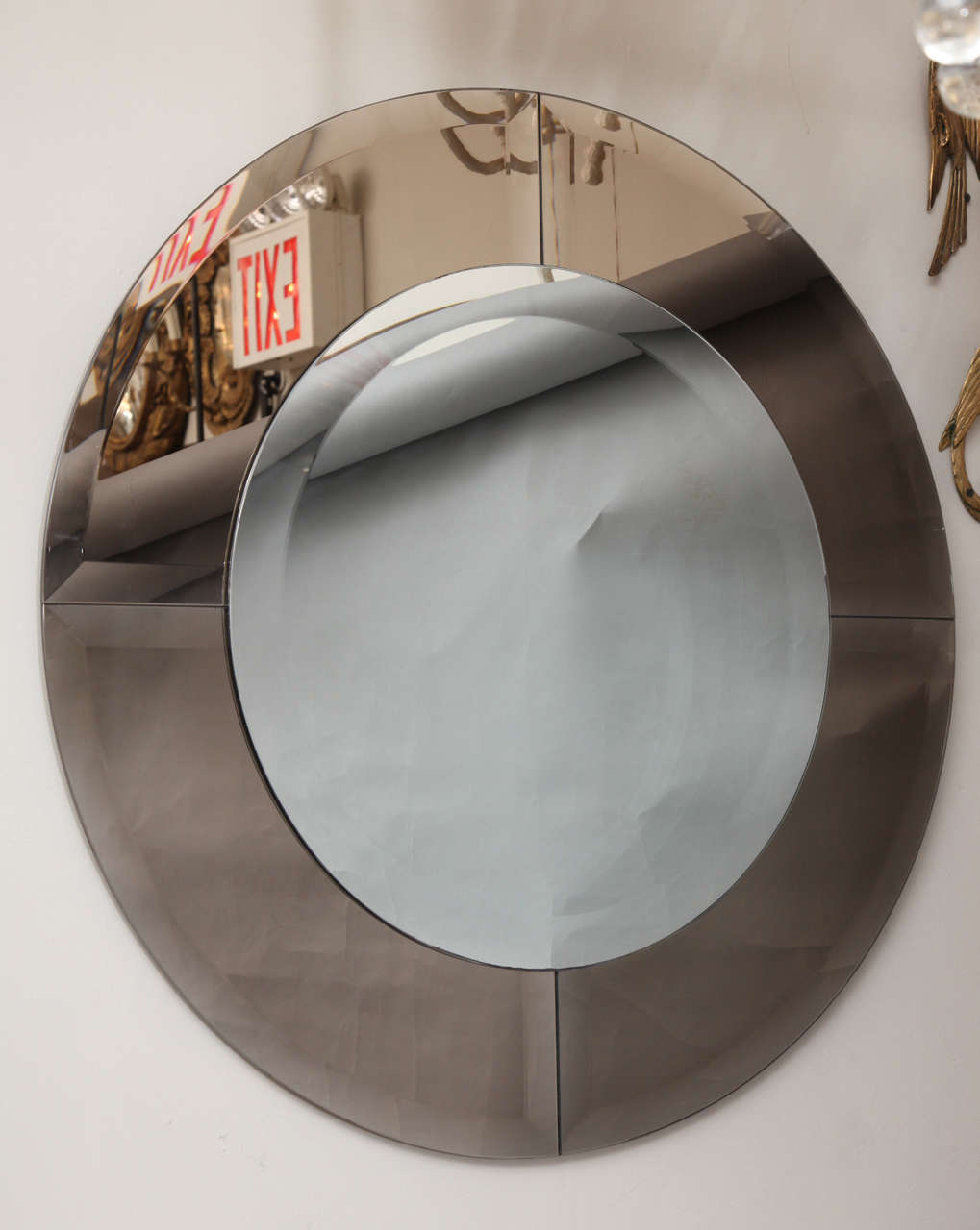 A round contemporary design mirror. The center glass with wide beveled edge framed by four sections of mirrored frame with deep beveled edge on four sides.