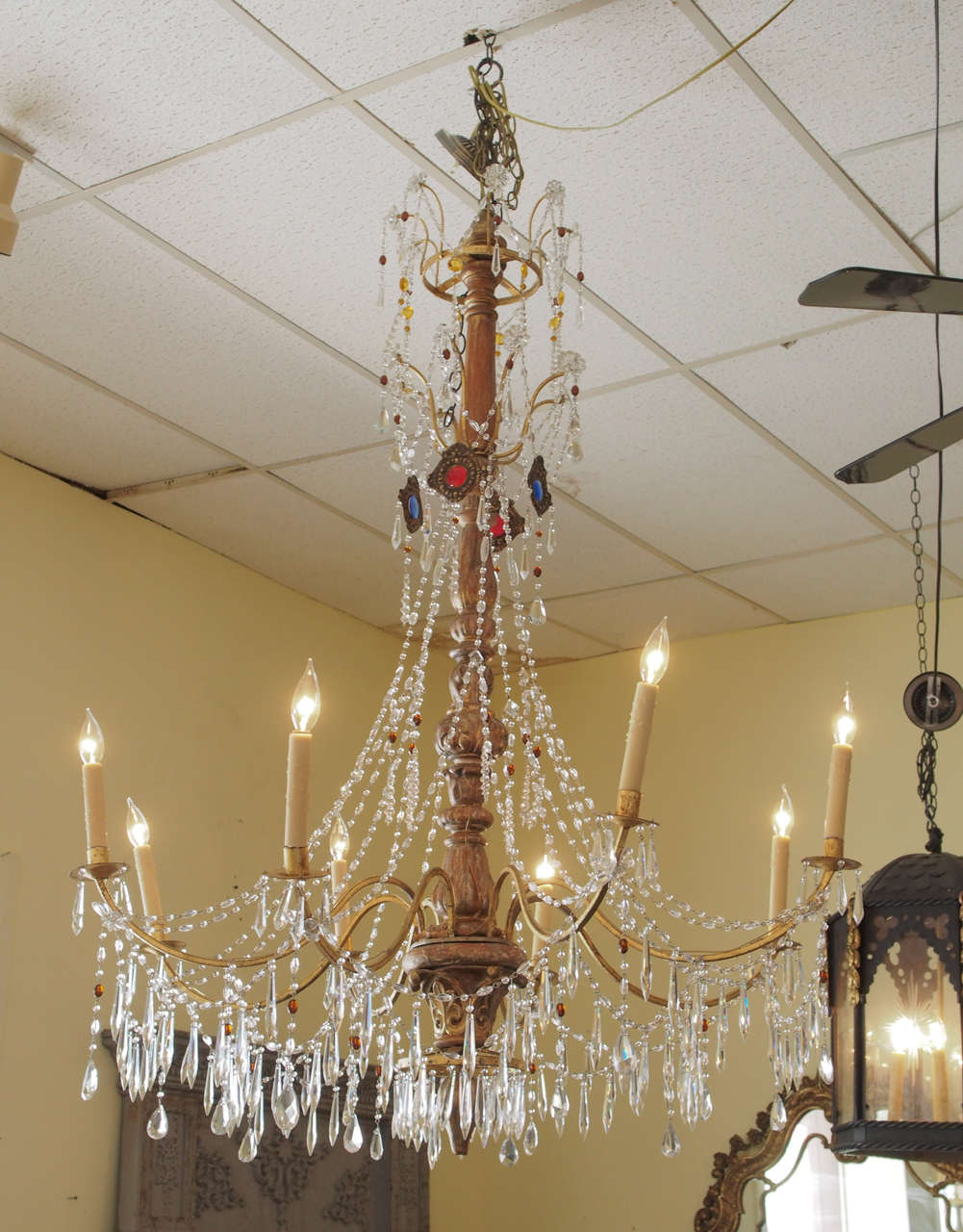 A spectacular, elegantly decorated late 19th century Genovese chandelier having a carved giltwood central shaft. The upper finial is surrounded by a gilt finish metal ring from which emanate eight arched gilt finish metal spokes adorned with crystal