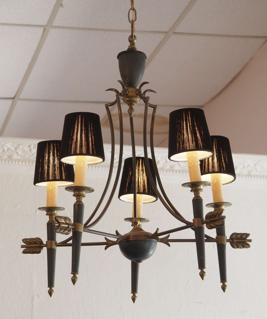 Elegantly simple bronze and patinated bronze Directoire style French chandelier, circa 1940. The five-candle like torches ending in beeswax sleeves surmounted with black translucent fabric shades are joined by bronze arrows to a lower central urn
