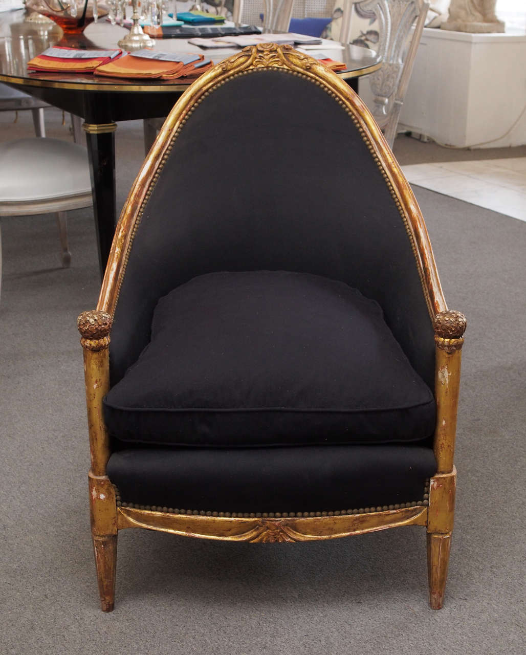 Handsome pair of carved giltwood and upholstered chairs in the manner of Emile-Jacques Ruhlmann, France, circa 1920.  The upper giltwood frame, having a Gothic arch-like shape and gracefully sloping arms, is centered with a carved floral motif.  The