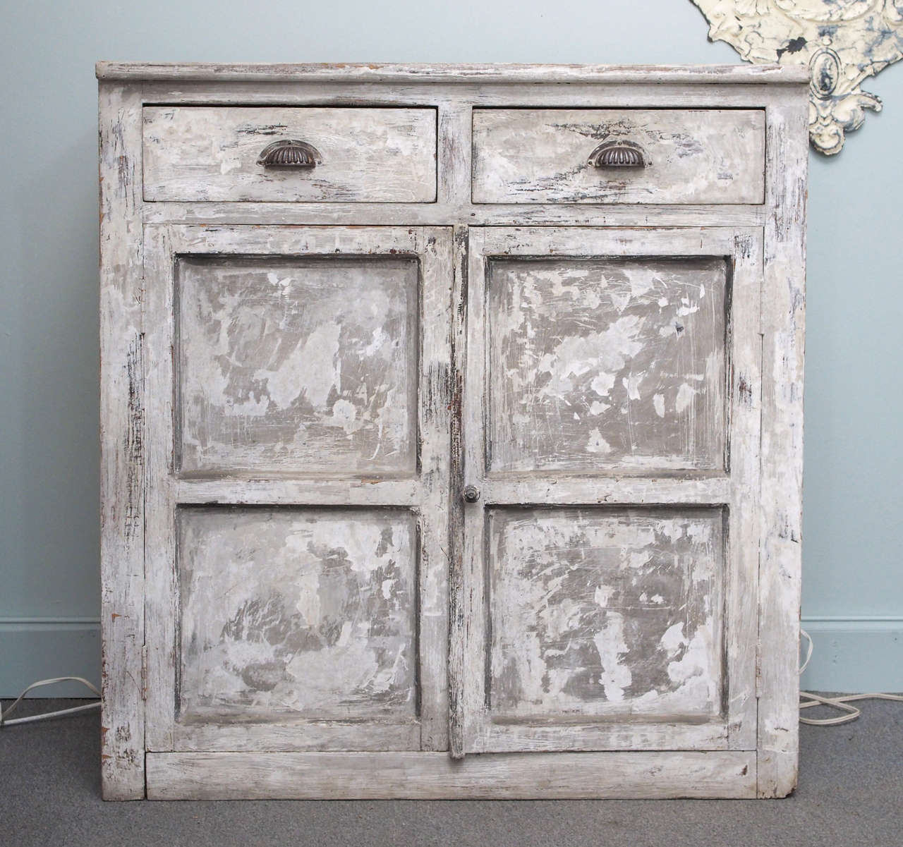 Painted rustic Italian cabinet, circa 1920-1930, having a rectangular top above a conforming case fitted with two upper drawers with brass cup handles and two lower paneled doors, one with a small carved wooden knob, opening to a single shelf.  The