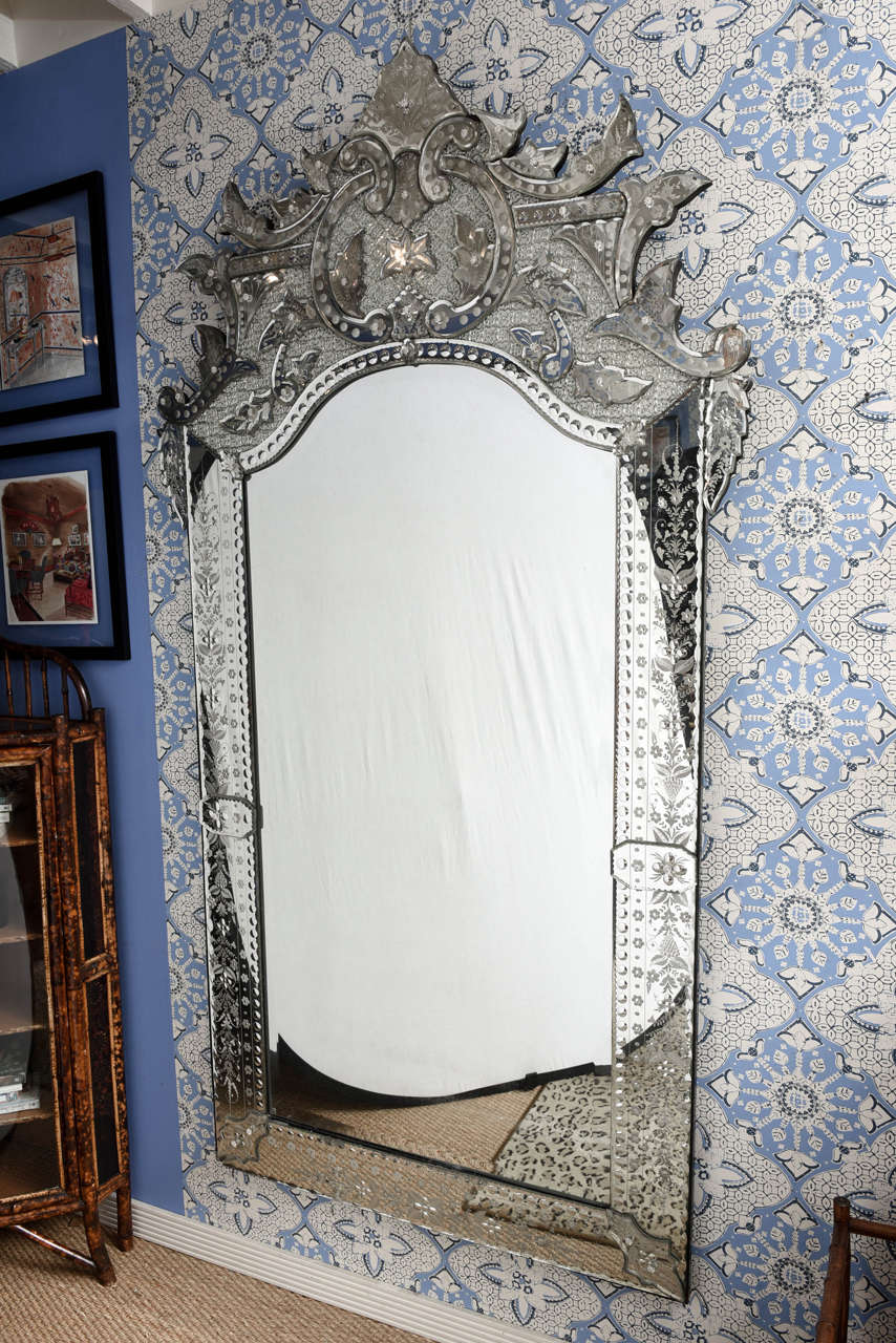 Large Venetian mirror, with engraved motifs on the frame and topped by an elaborate finial. (Stunning piece).
