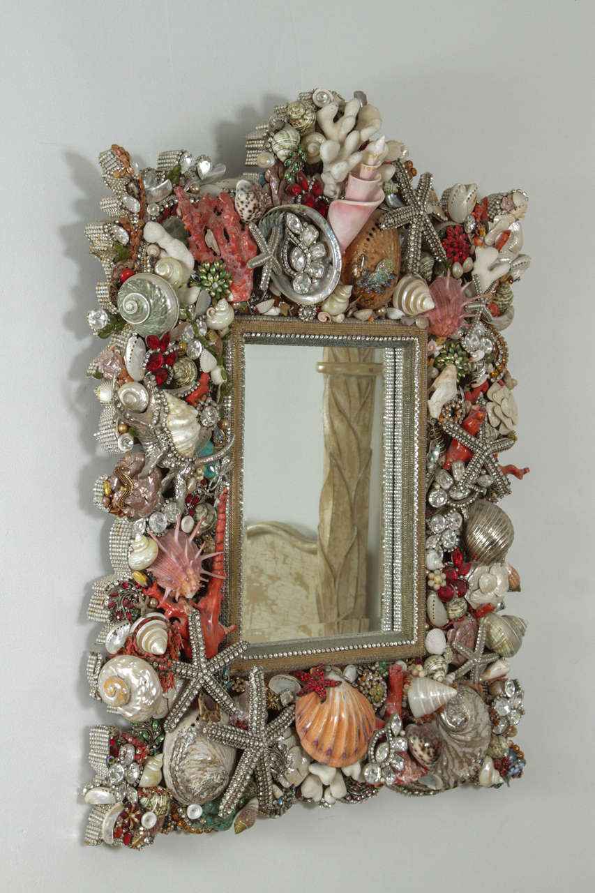 Spectacular mirror by Douglas Cloutier.
The handmade  elaborate one of a kind mirror which consists of Swarovski crystals, vintage costume jewelry, seashells and coral make this a truly stunning piece of Art which will add glamour to any decor.