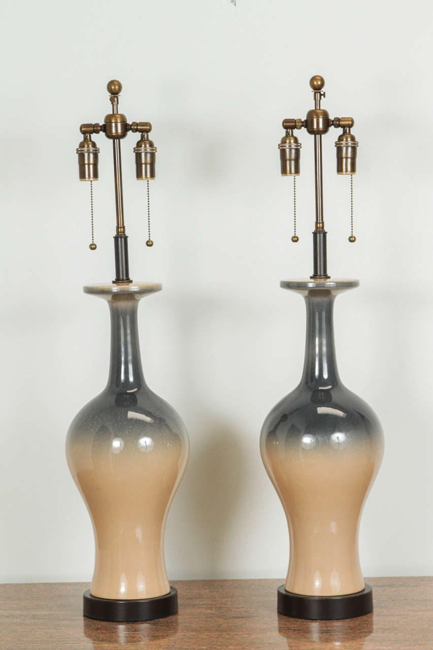 Pair of stylish table lamps with an ombré glaze of gray fading into a pale tan.
They are newly rewired and are outfitted with antique brass double clusters.