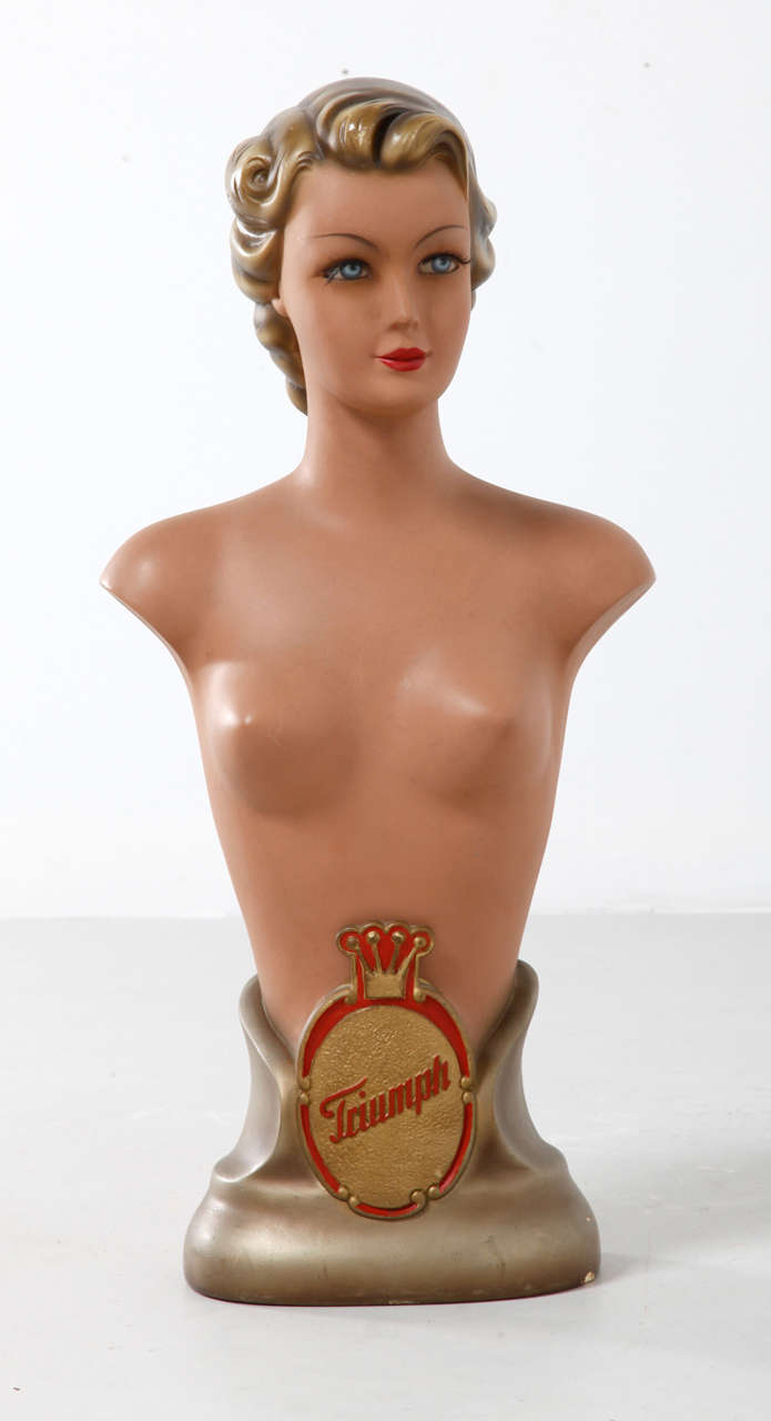 A shop advertising mannequin, a three quarter body doll from the 1930's advertising the Triumph Bra with the logo to one side. She measures high 72cm and condition is very good.