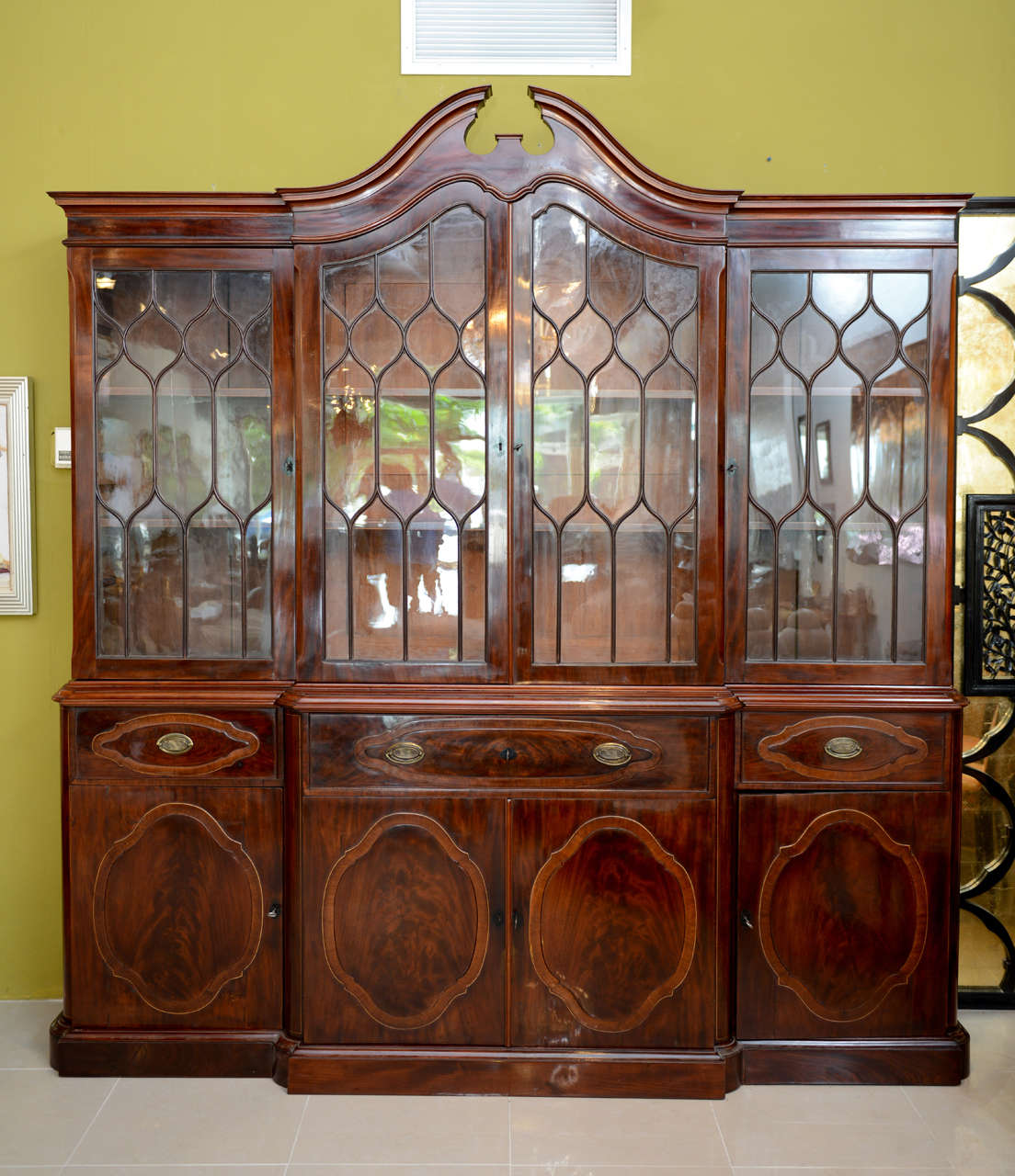 The arched broken pediment top above four doors with glazed grillwork over four drawers and four doors, in the George III style.
