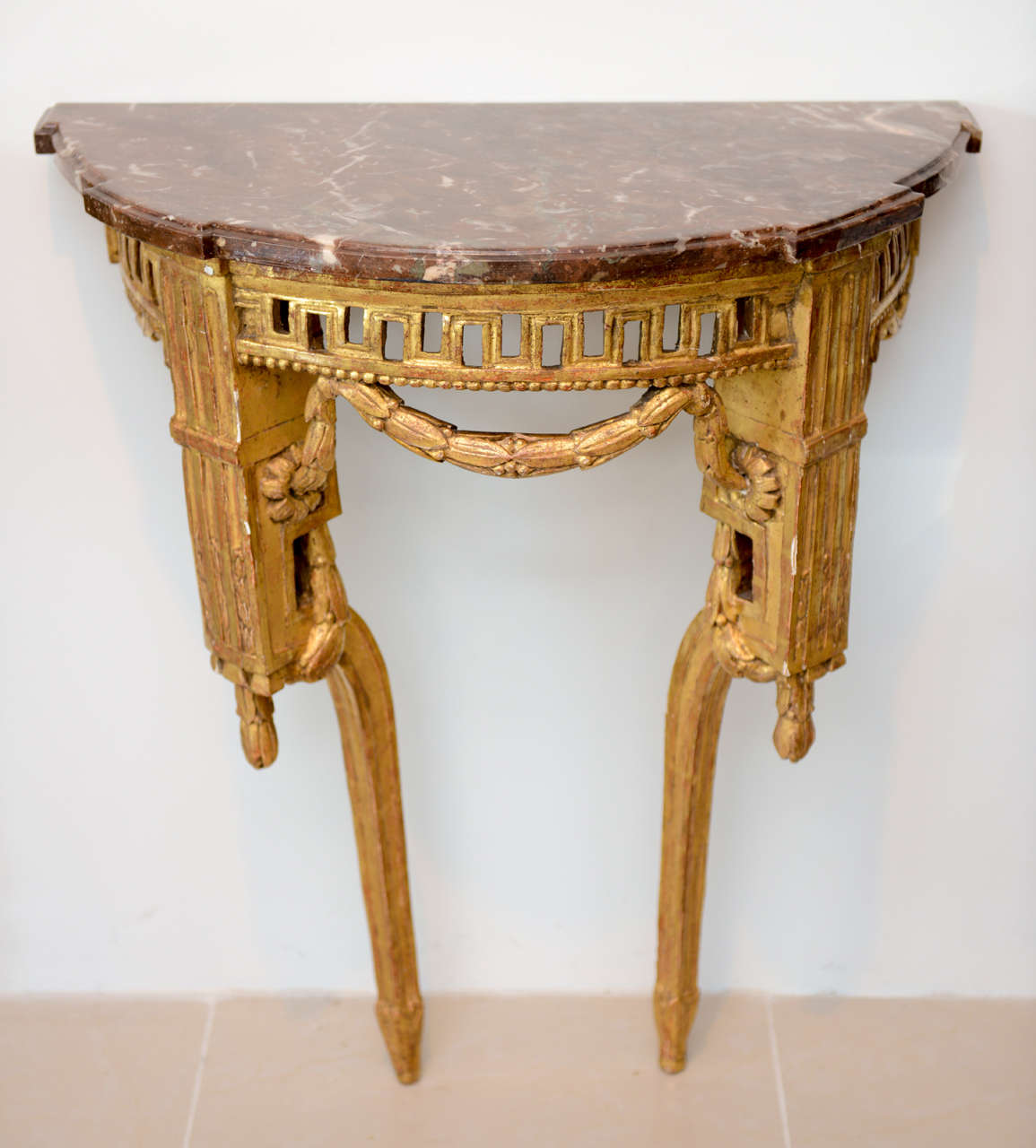 The rosso marble top above a pierced frieze with modified key motif, with carved swags and fluted elements on splayed legs.
