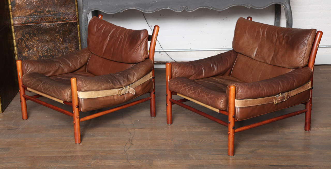 A fantastic pair of Arne Norell brown leather chairs with wood frame and leather straps secured with original antique brass buckles.
Very roomy and comfortable with buttery original leather,all cushions in perfect soft condition.